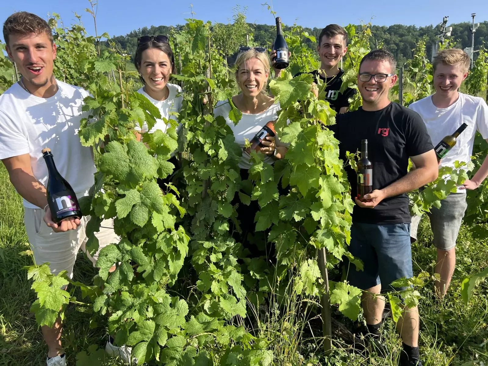 Gruppenbild der next generation zwischen den Weinreben mit ihren Produkten